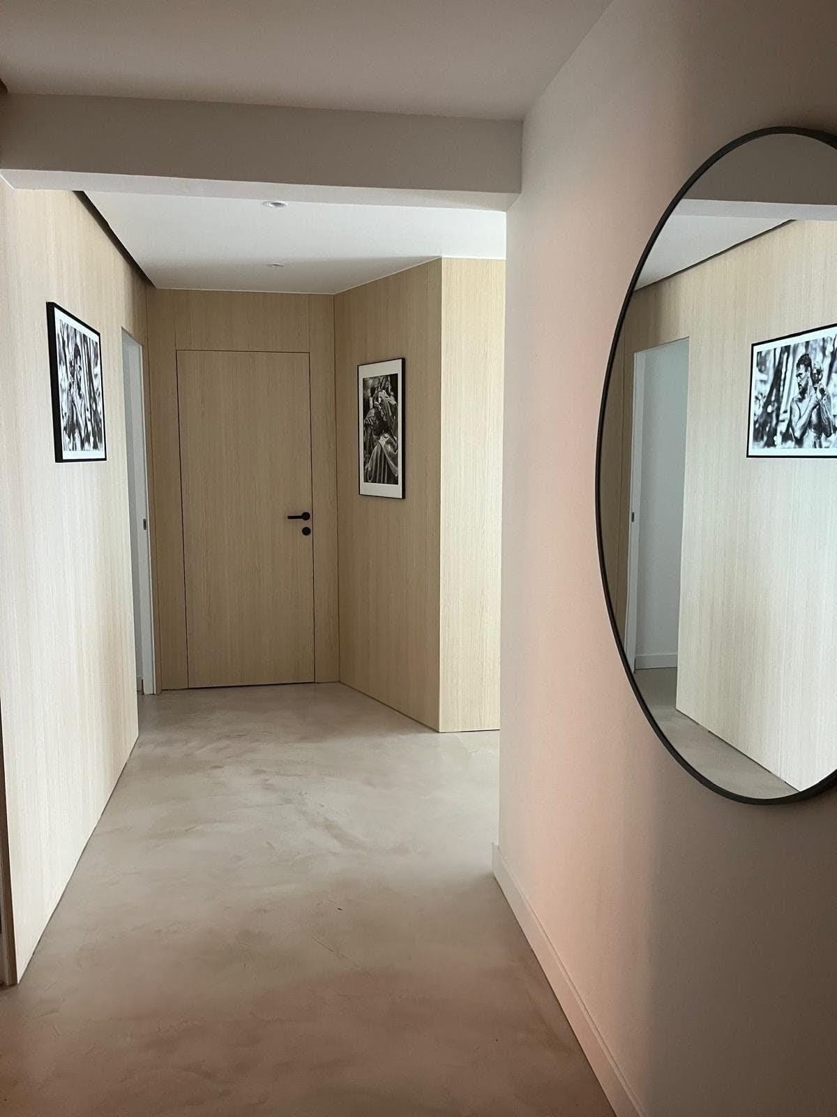 Hallway with light oak wall panelling, black-and-white framed prints, and a round mirror